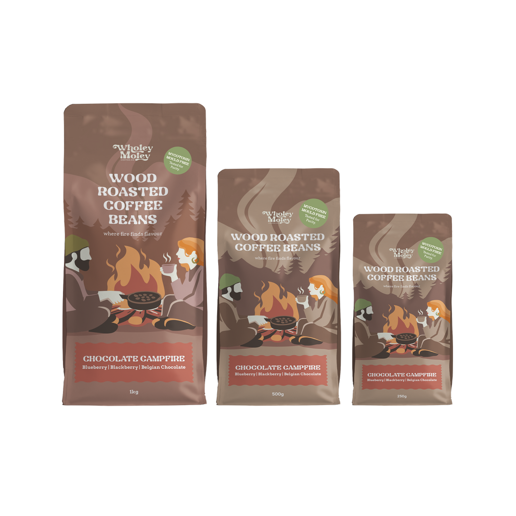 Three bags of Wholey Moley Wood Roasted Coffee Beans in different sizes, featuring a brown and orange campfire illustration on a white background.